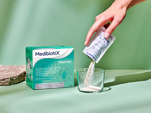 Blaue Medibiotix Mental Packung neben einem Glas.