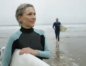 Mann und Frau am Strand mit Surfbrettern in der Hand.
