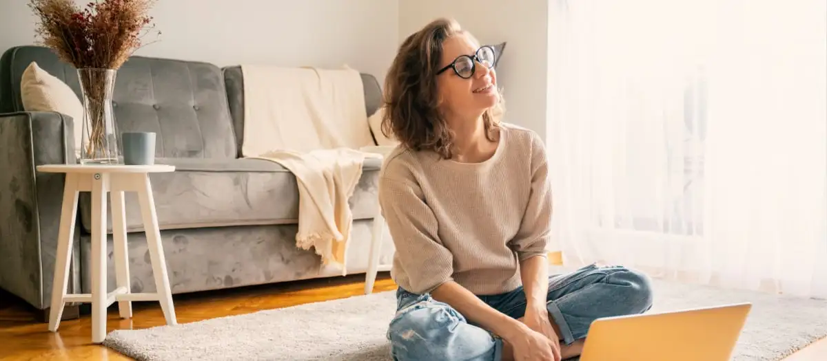 Frau sitzt auf dem Boden vor ihrem Laptop.