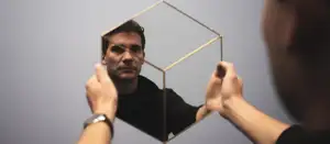 Mann schaut sich in Spiegel an.