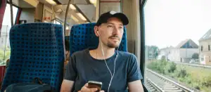 Mann sitzt im Zug und hört Musik.