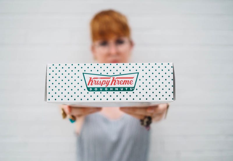 Krispy Kreme staff member holding a box of doughnuts