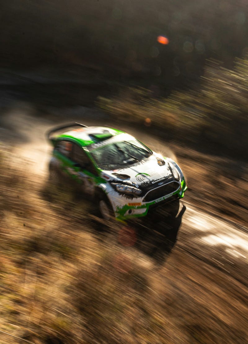 Rally car moving at speed along a dirt track