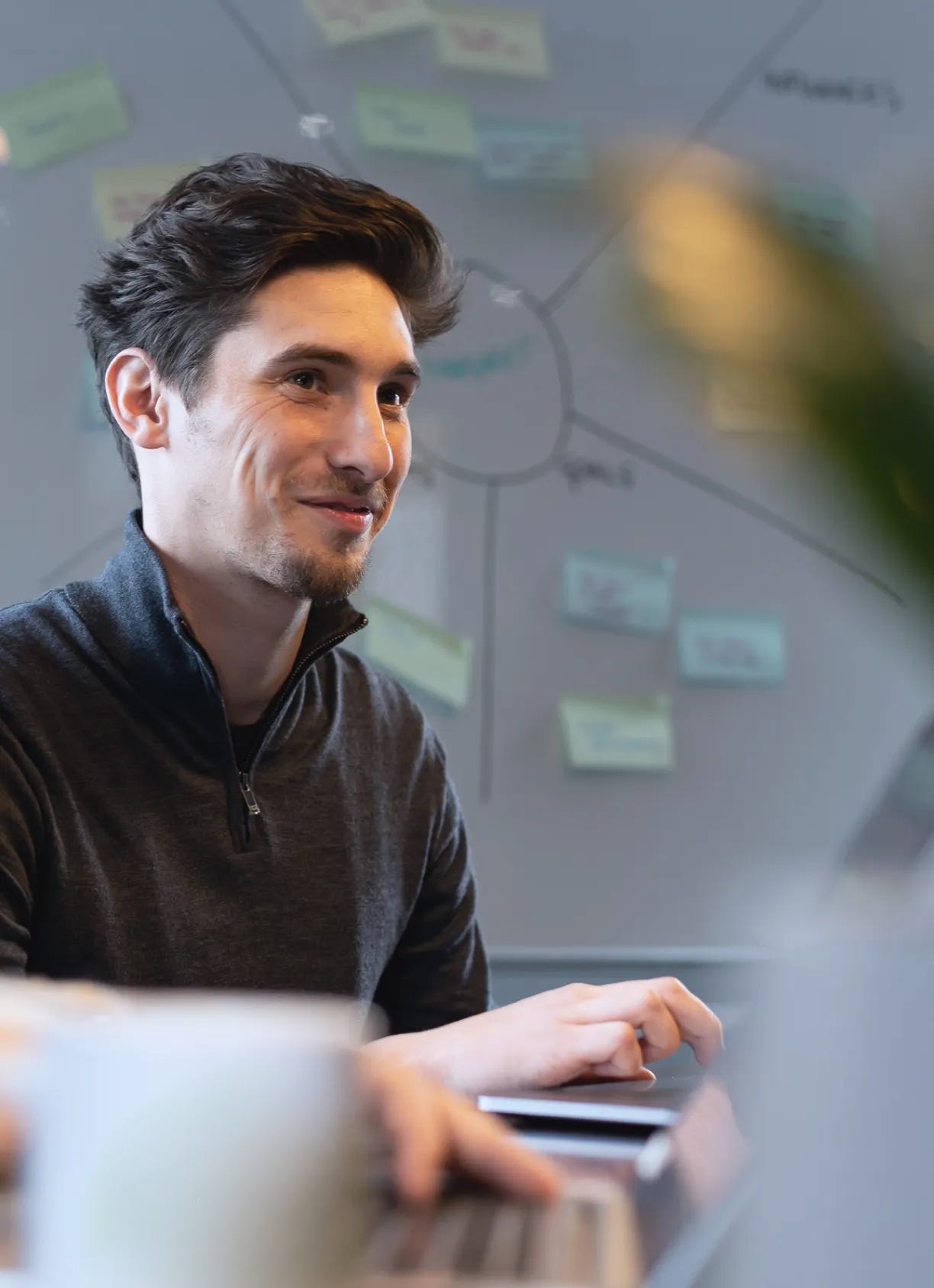 A man sat in a meeting in front of a whiteboard