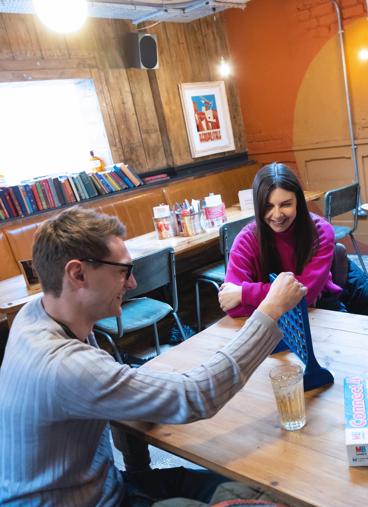 A man and a lady playing Connect 4 inside a pub