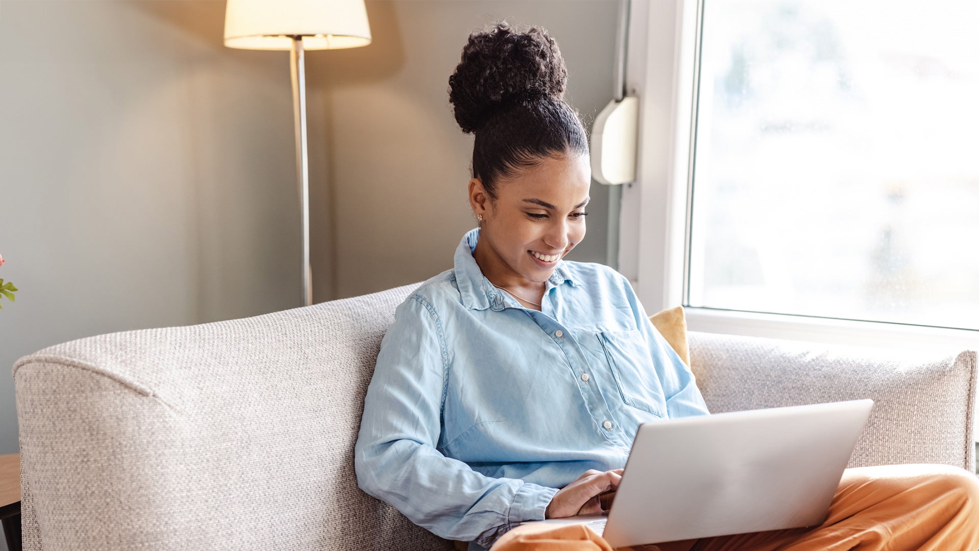 Someone sitting on a sofa with a computer on their lap