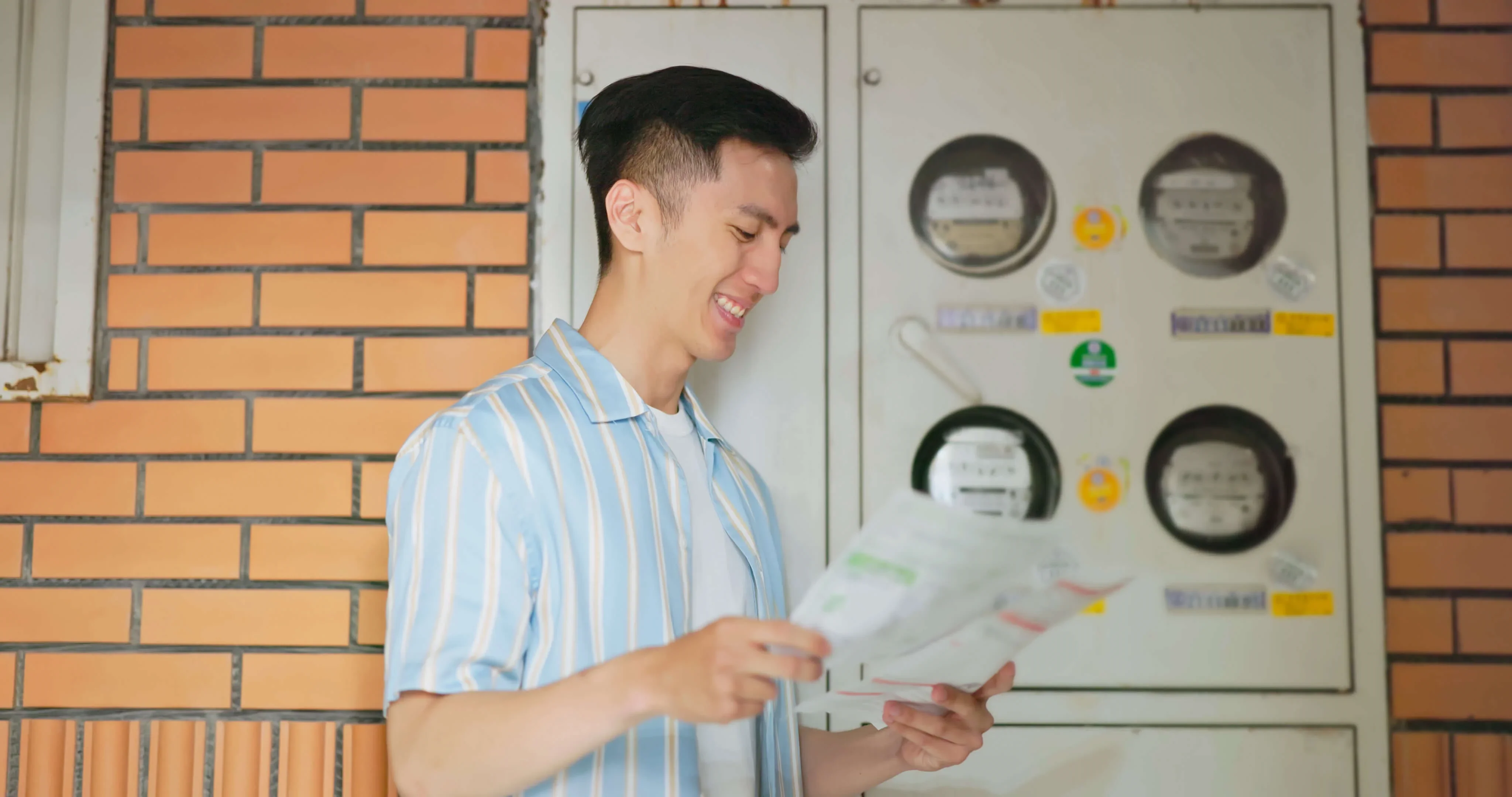 A happy business stands next to his energy meters and check his energy bills
