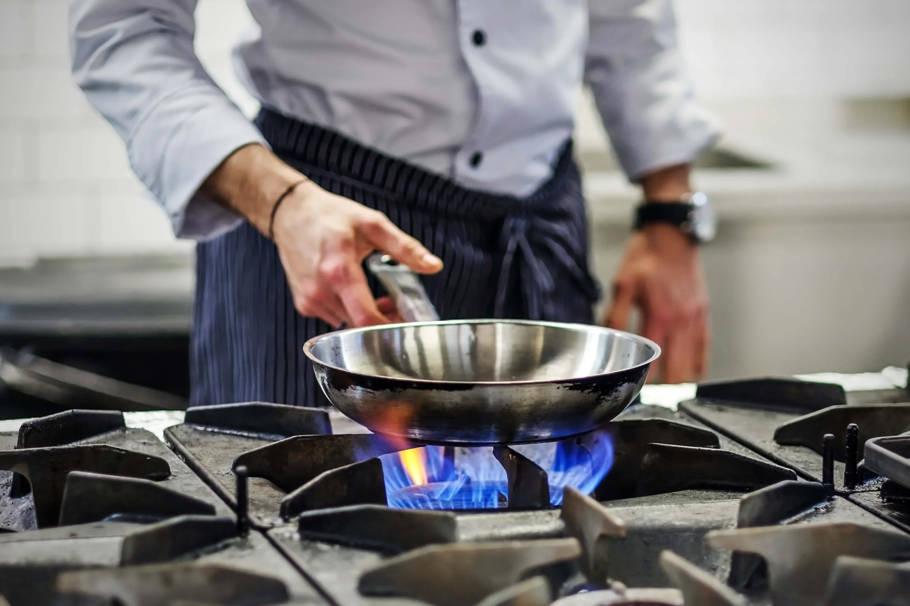 A chef heats up a pan on a gas fired stove