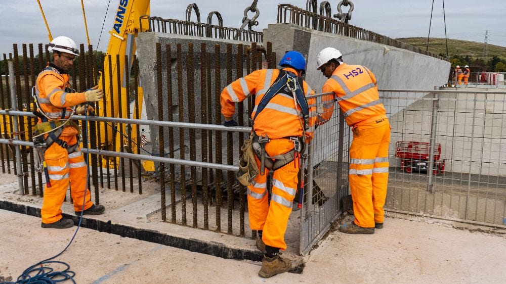 HS2 construction workers wearing orange overalls and hard hats at bridge construction.