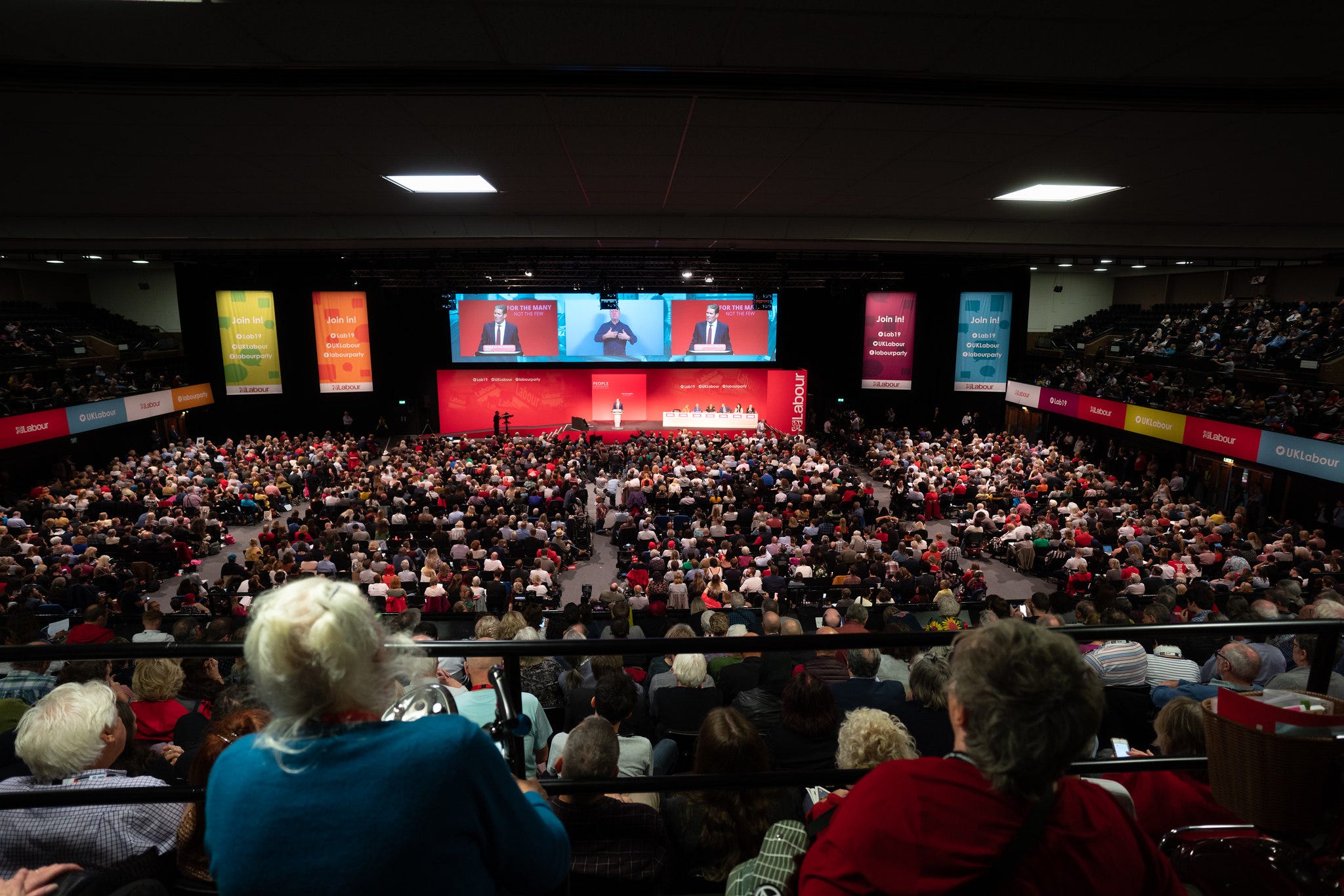 Head-on shot of Labour Party conference hall, Brighton 2019, showing rows of seated delegates, stage and big screen