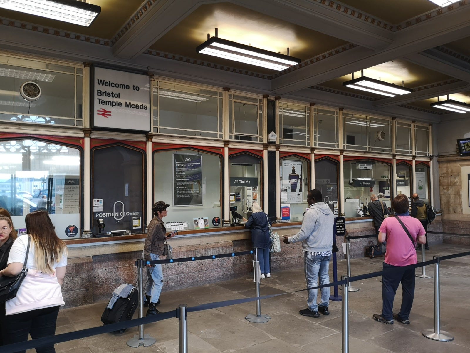 Bristol Temple Meads station ticket office. There are people waiting to be seen byt staff. 