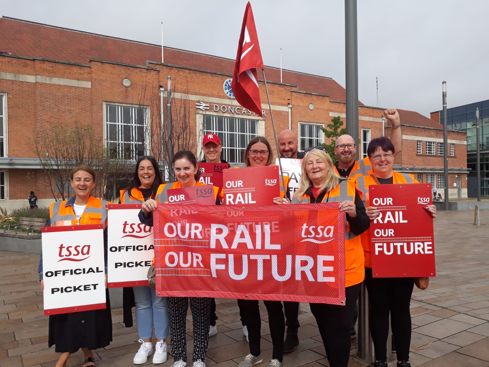 Image shows picket line with TSSA's Andi Fox and eight other TSSA members wearing hi-vis jackets on strike in Doncaster
