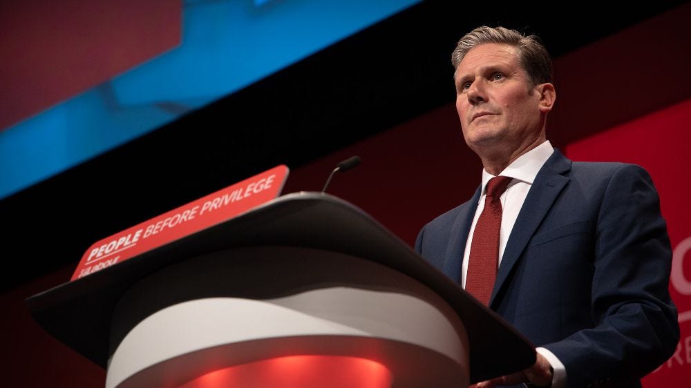 Keir Starmer MP speaking fron the rostrum at Labour Party conference with slogan 'people before privilege'