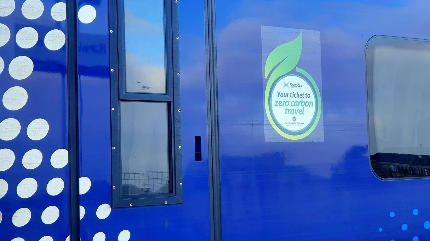 Blue ScotRail train with green logo saying ScotRail your ticket to zero carbon travel