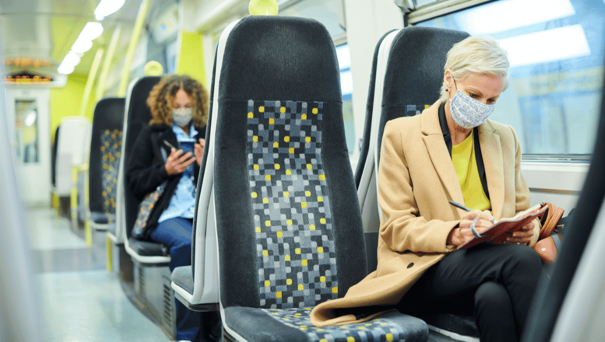 Passengers wearing face masks sat on bright tube train