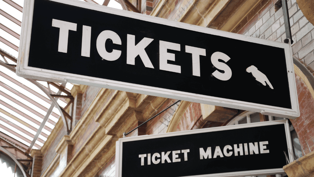 Ticket office sign in train station, above smaller sign saying 'ticket machine'.