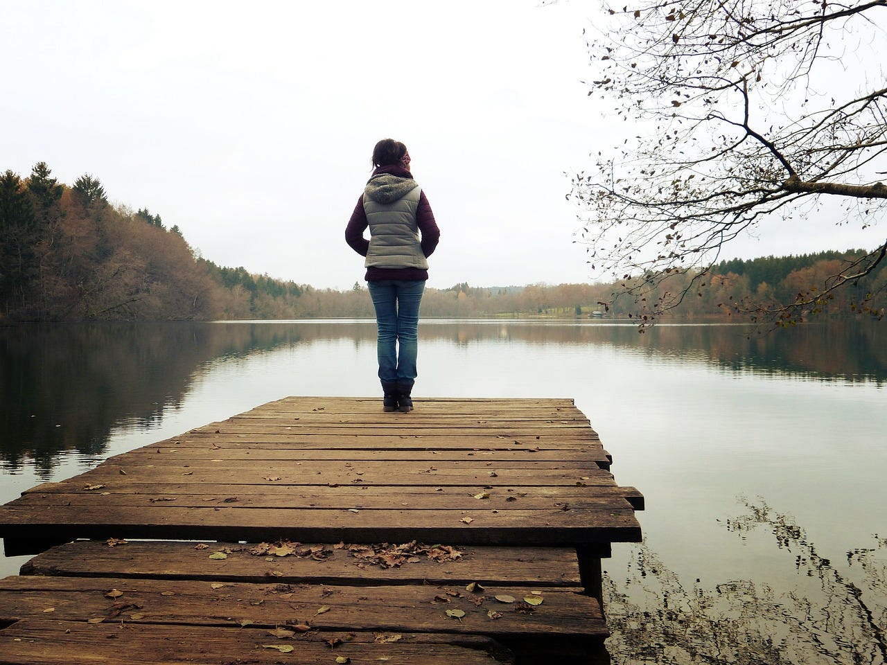 Women standing on dock facing towards a lake.