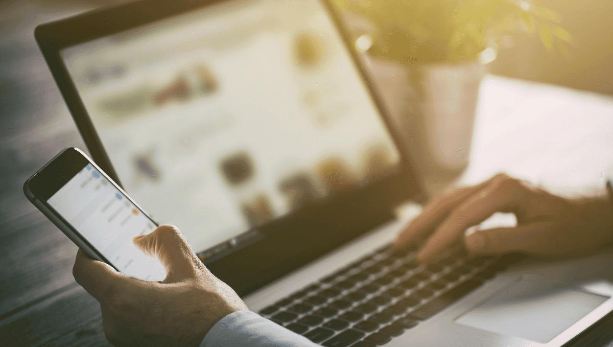 Close up of a man working on a phone and laptop