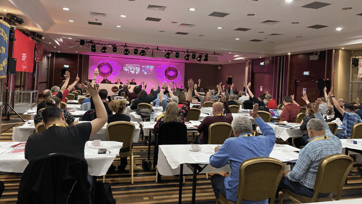 Conference hall with delegates' hands up voting