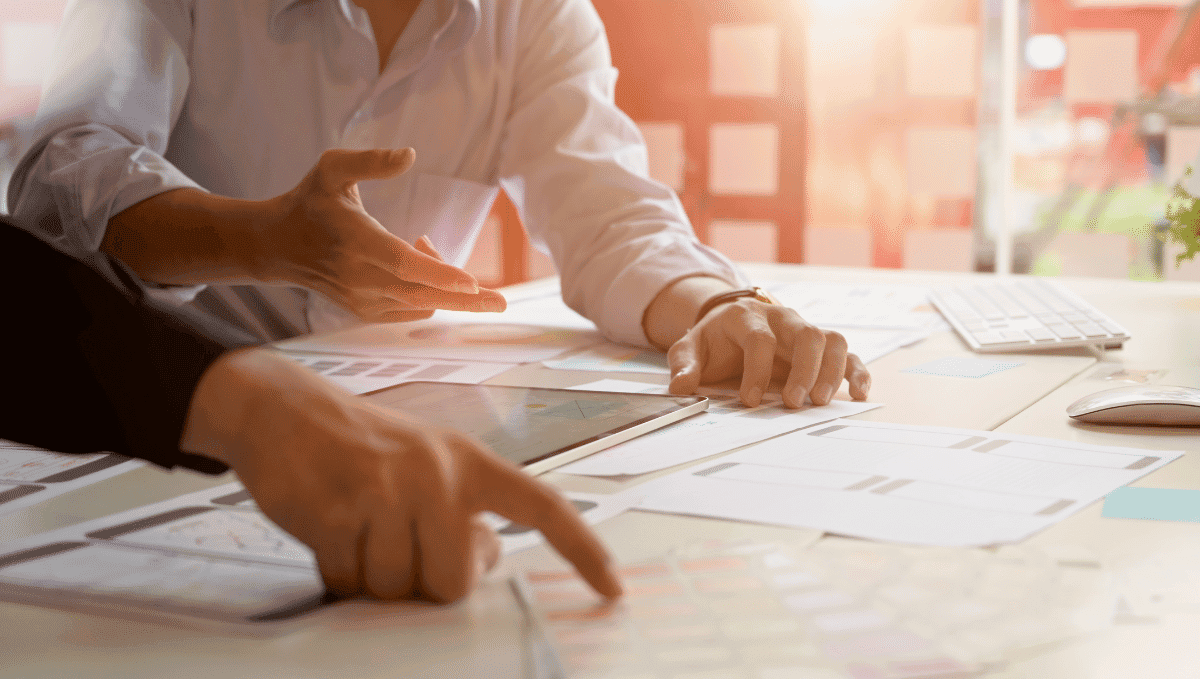 Close up of people working together at a desk pointing at paperwork.