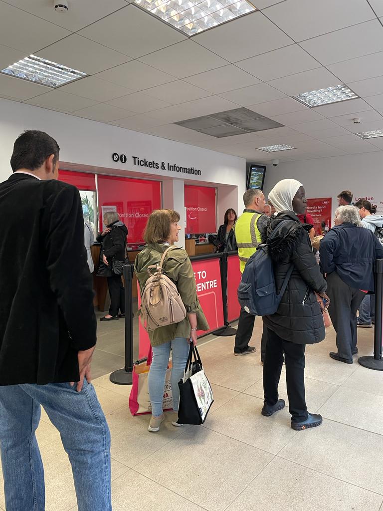 A long queue of people of different ages and races at the Darlington ticket office window