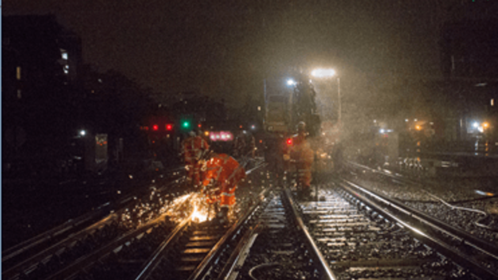 Network Rail engineers working on tracks at night with metal sparks shining in darkness