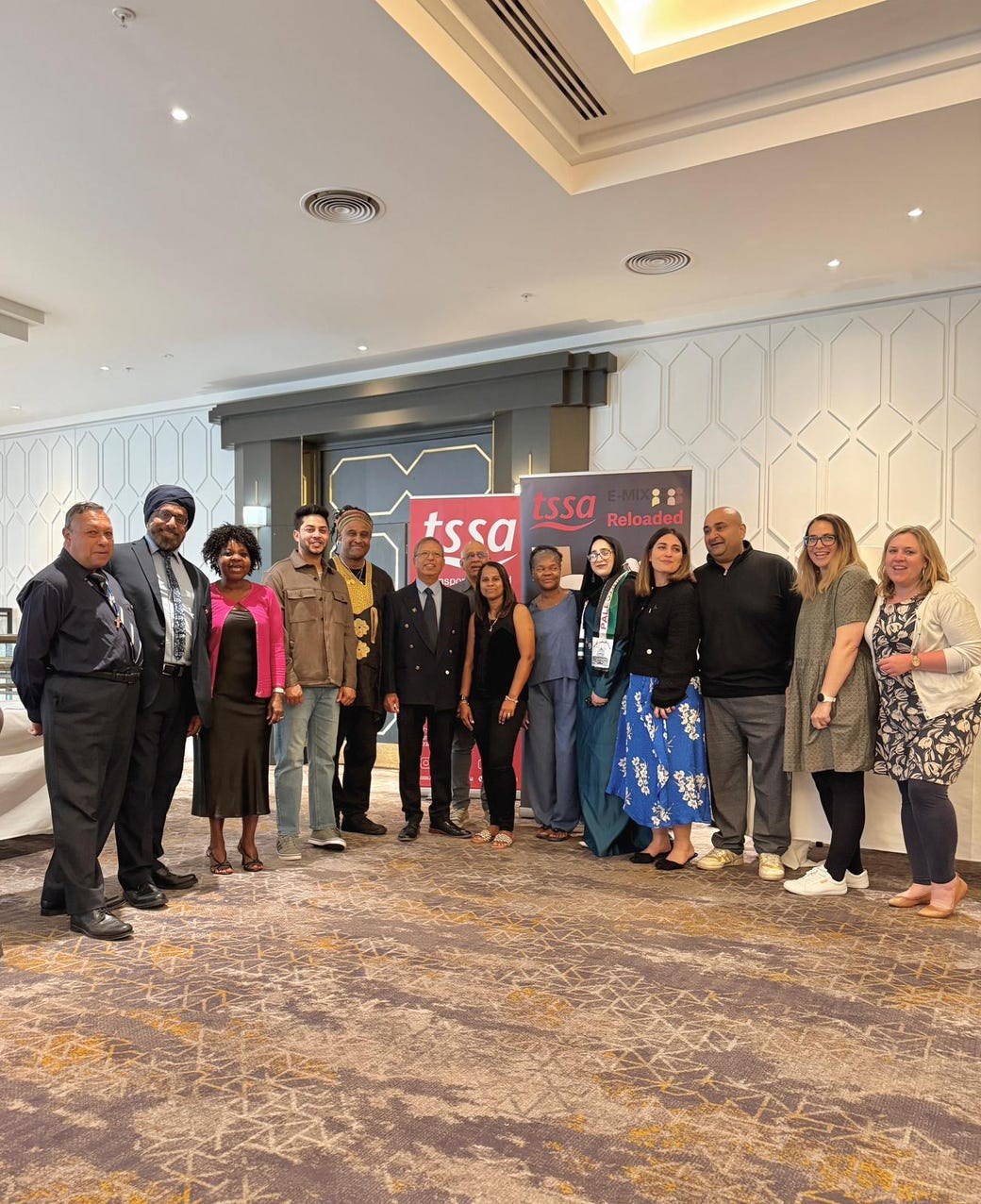 Fourteen E-Mix members standing in front of the TSSA and E-Mix banners at Annual Conference in Belfast. 