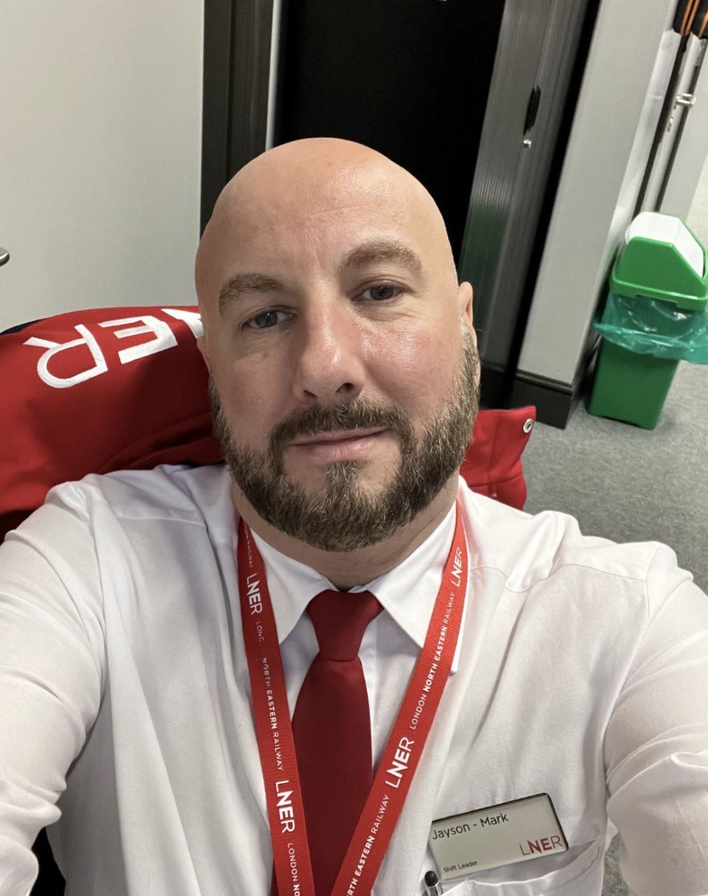 A bald man with a well trimmed beard takes a selfie.