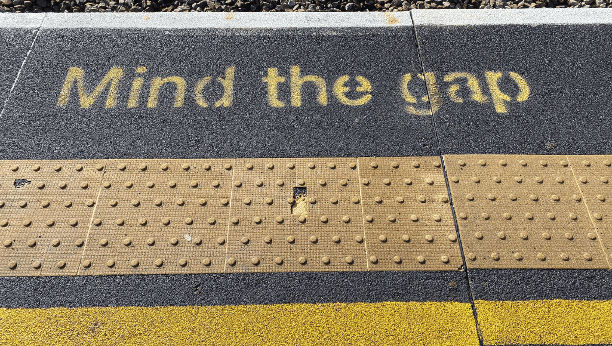 Mind the gap sign written in yellow on station platform