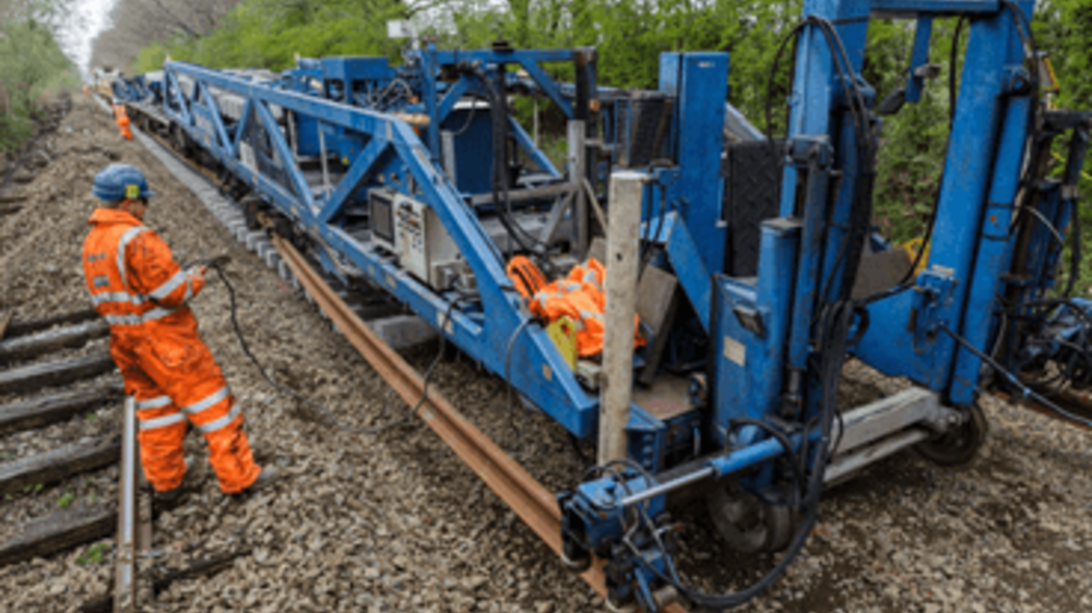Network Rail engineer in orange high vis working blue track machinery