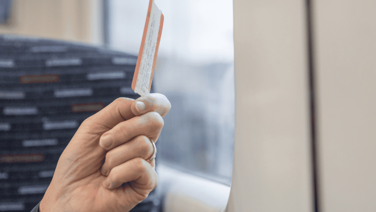 Close up of a hand holding a train ticket on a train