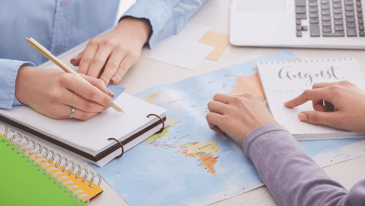 Holiday booking picture showing map, desk and people writing notes