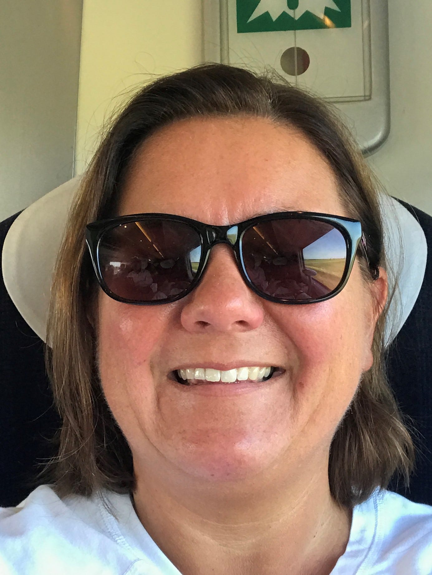 A selfie of Catherine Poole, she is wearing sun glasses and sitting on a train.
