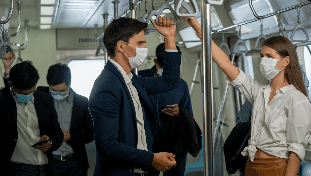 Commuters wearing face masks standing in train carriage.