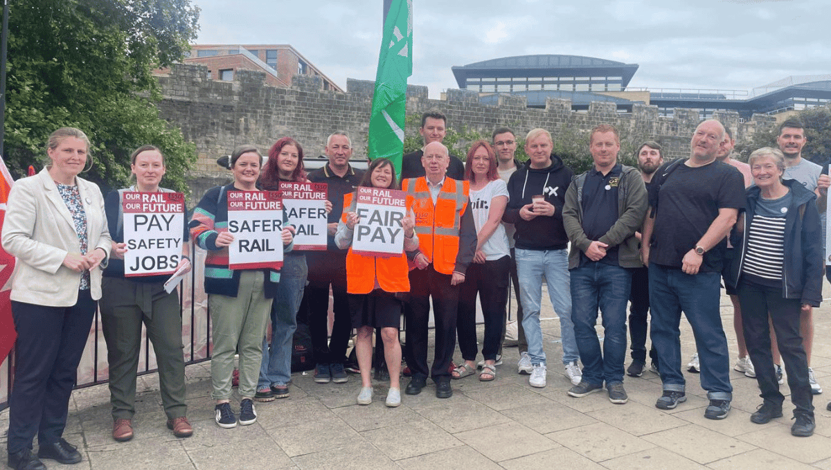 Large picket line at York station with placards and Rachael Maskell MP