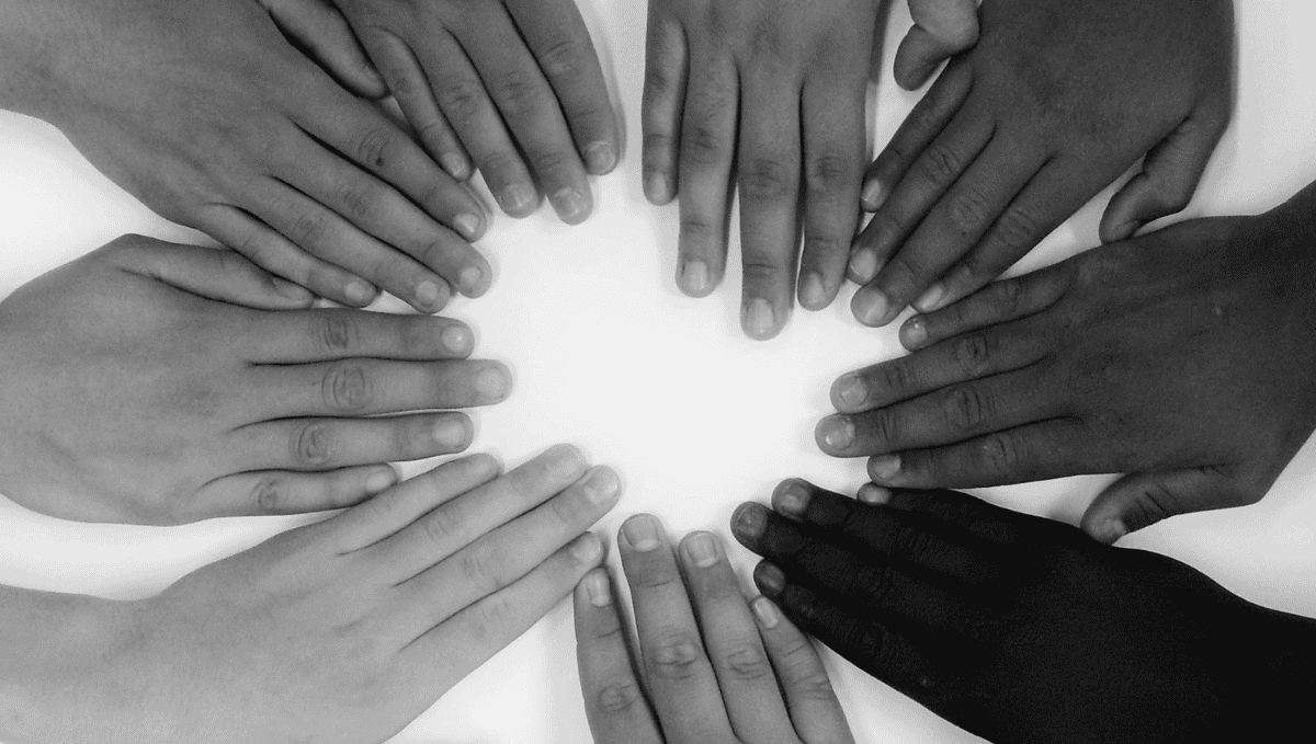 Black and white photo of hands of different backgrounds in a circle