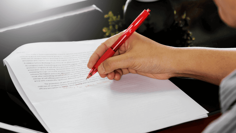 Photo of someone correcting a printed document with red pen