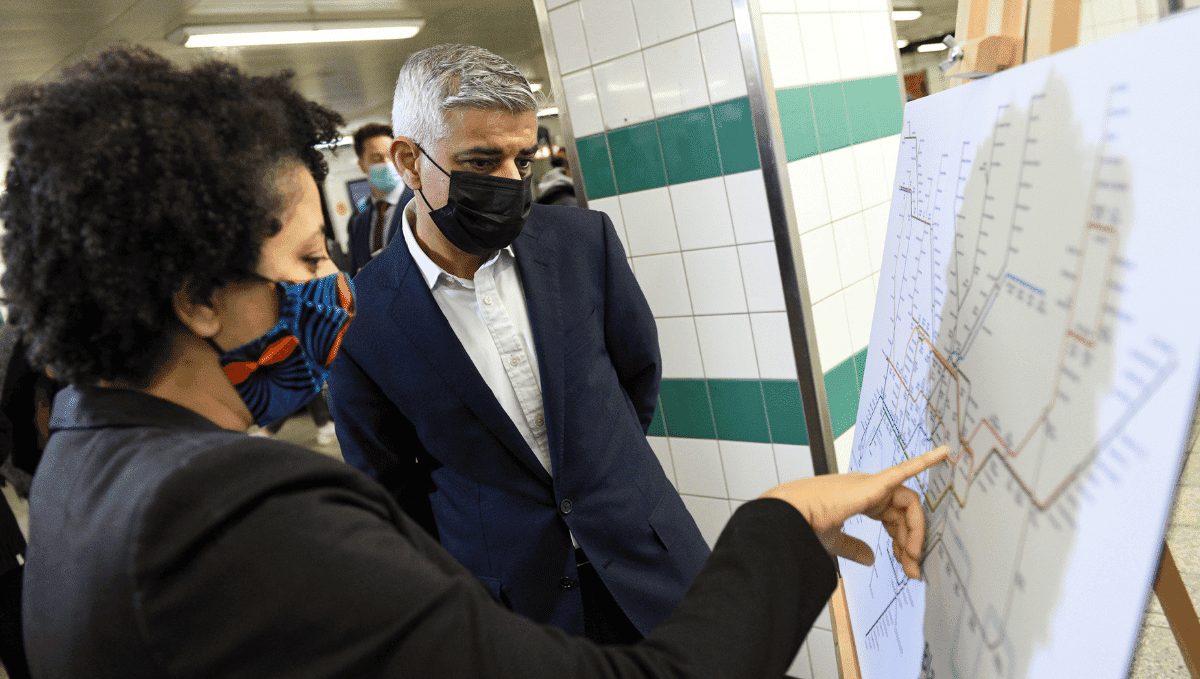 London Mayor Sadiq Kahn looking at Black history tube map with a woman, both wearing face masks.