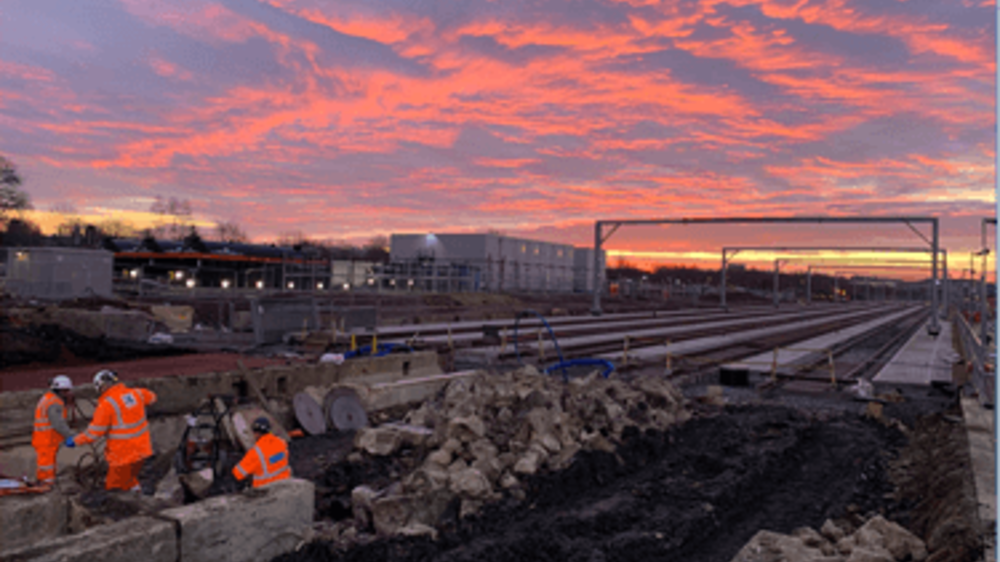 Network Rail engineers in high vis working on tracks under a pink sunset sky