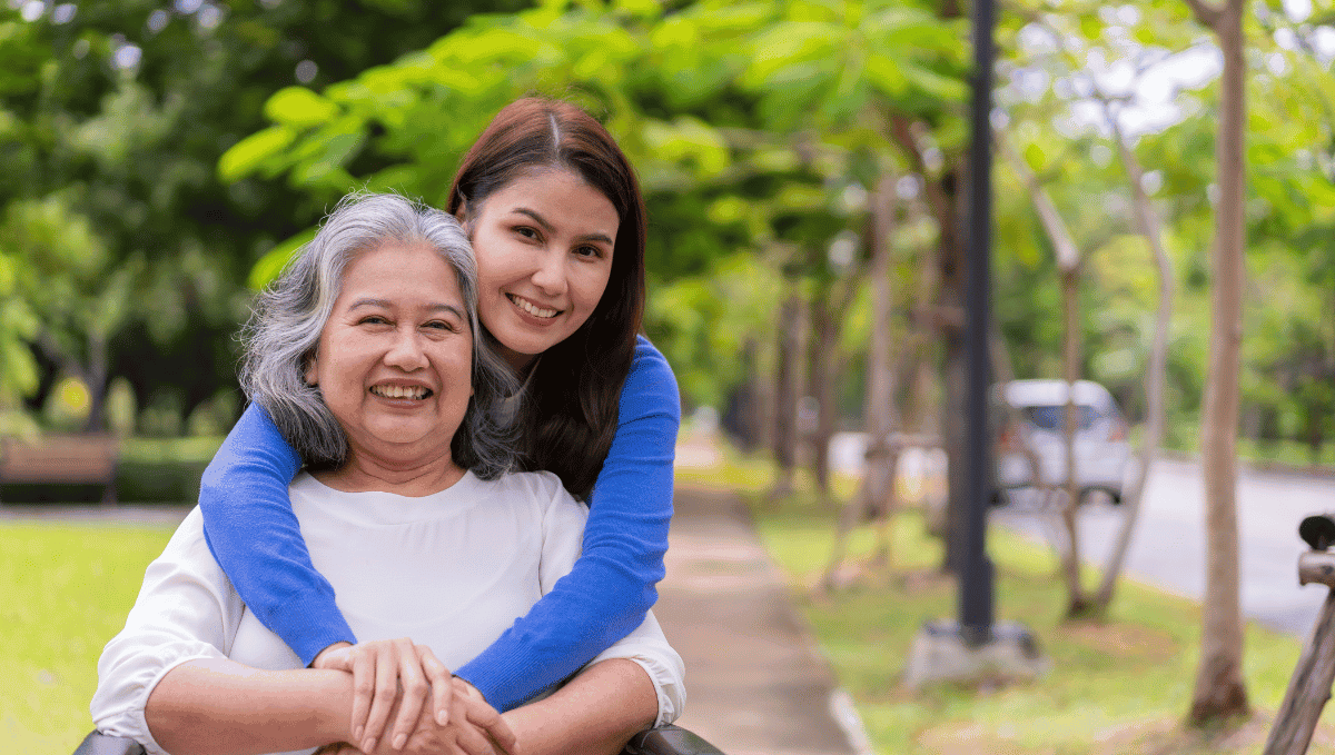 Older woman in wheelchair and younger woman hugging her. Depicting carer.