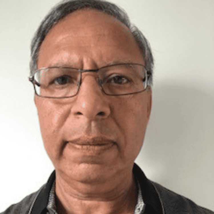 Dinesh Bhardwa, an older Asian man with grey hair and rectangular glasses, looking directly at the camera.