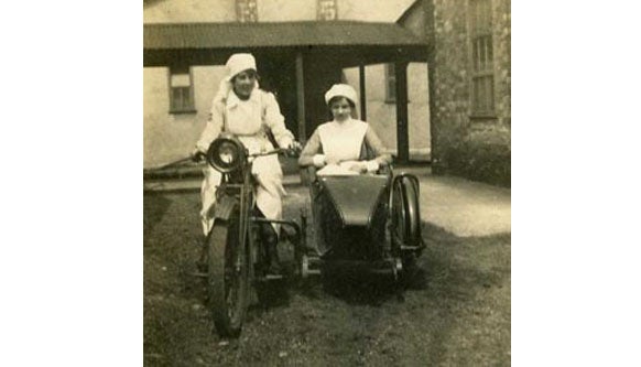 Two Red Cross nurses looking a bit unsteady on a motorbike during WW1.