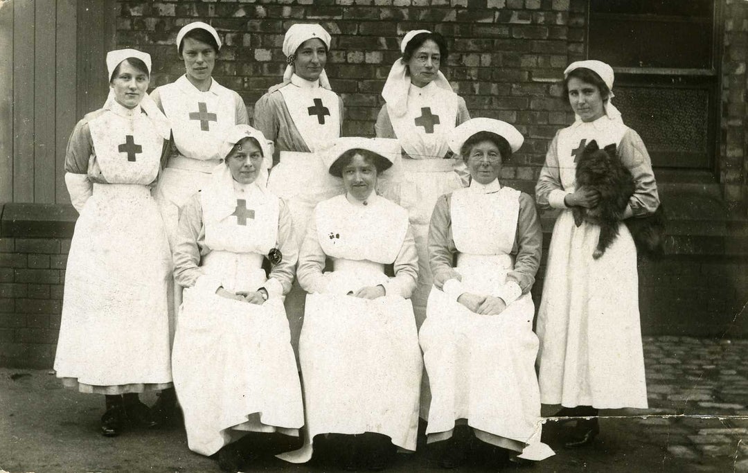 A group of Red Cross nurses, one of whom is holding a cat