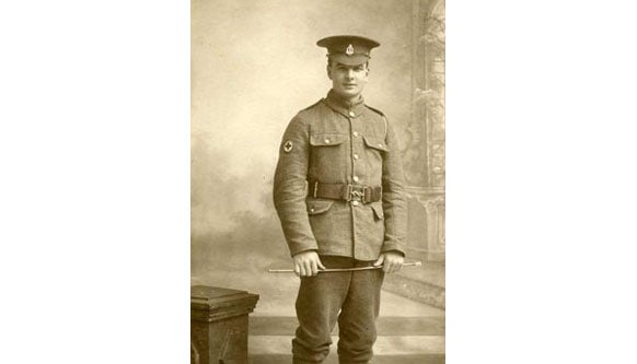 Sepia photo of soldier standing with Red Cross badge on sleeve