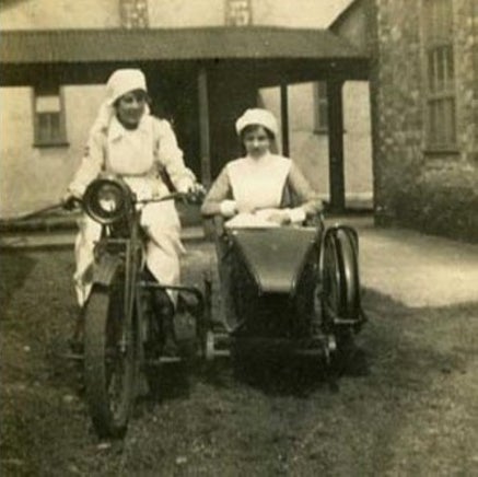 Two Red Cross nurses looking a bit unsteady on a motorbike during WW1.