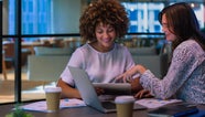 Two women in the office leaning over an ipad