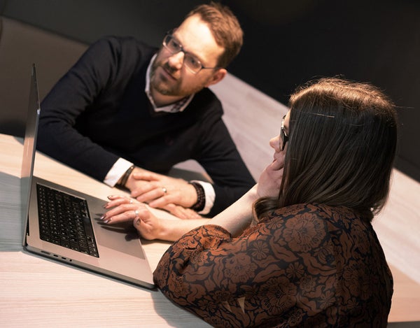 Two 26 employees sat around the table looking at a laptop.