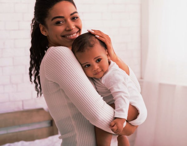 A person holding a newborn and smiling.