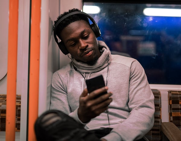 Person on the tube wearing headphones and looking at their phone