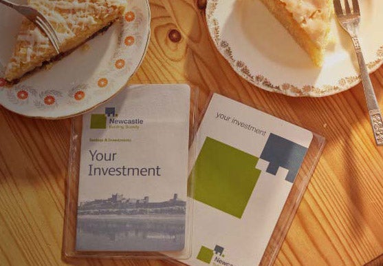 Two Newcastle Building Society passbooks on a table, surrounded by two plates with slices of pie on them.